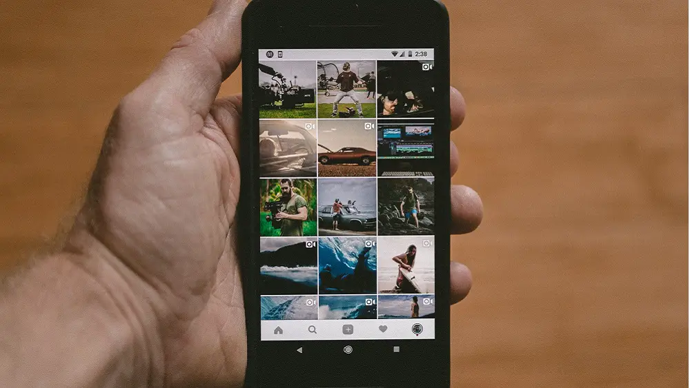 Instagram feed on phone in man's hand - Build Your Brand on Instagram